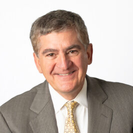 Man wearing a gray jacket and yellow tie smiling